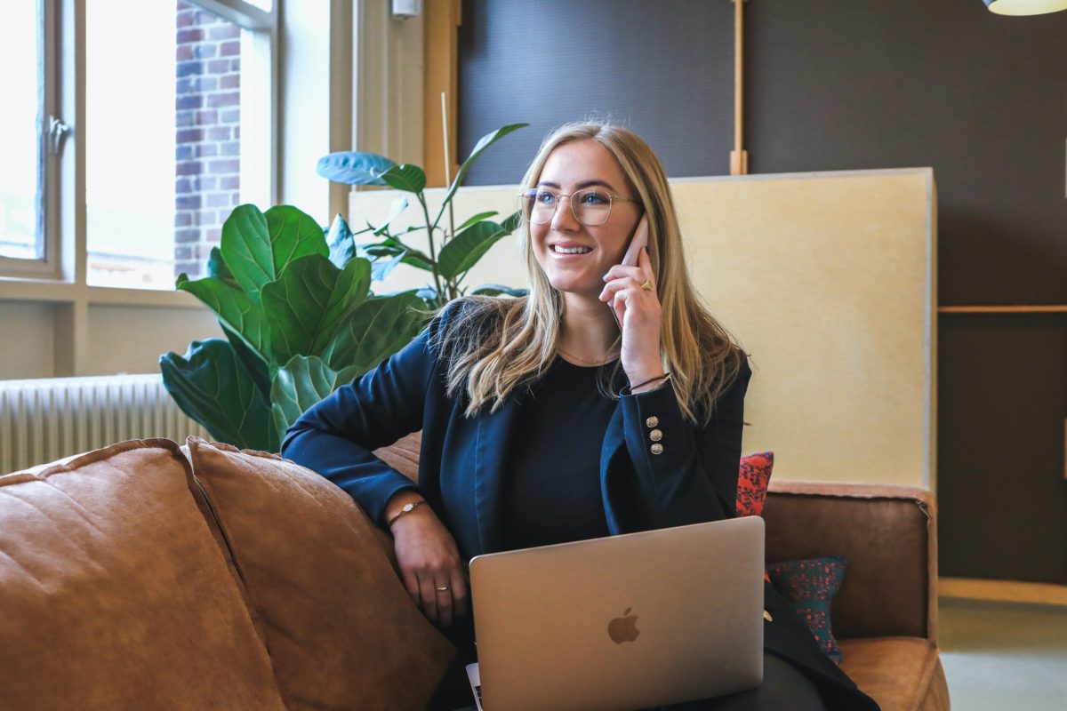 A smiling professional taking a phone call with her laptop open